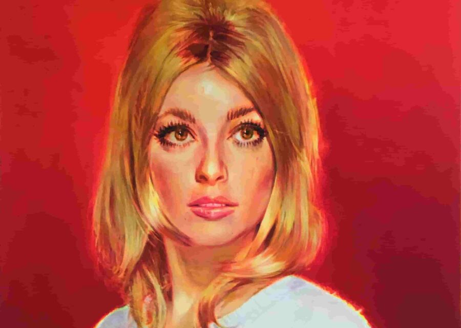 Portrait d'une femme blonde portant un pull blanc sur fond rouge.