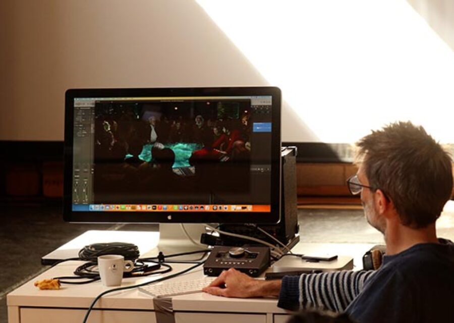 Un homme est devant un ordinateur et travaille au découpage des scènes d'un film.