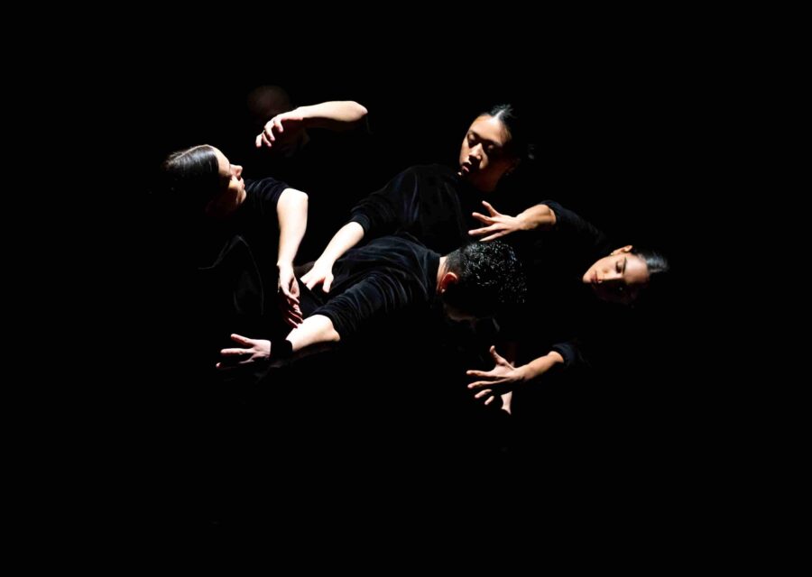 Les visages et les mains de danseurs et danseuses dans un clair-obscur.