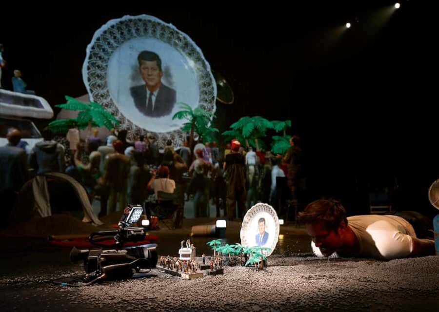 On voit l'installation miniature avec les personnages et arbres en plastique et l'image ainsi créée projetée sur grand écran.